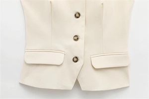 Detail of cream women's waistcoat showing marble buttons and flap pocket texture