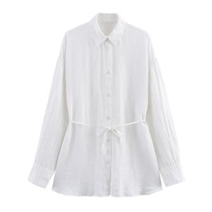 Détail d'une chemise en coton blanc avec une fine ceinture nouée en forme de nœud