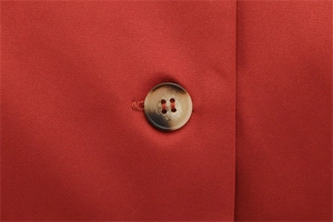 Macro detail of high-quality red fabric texture with a classic tortoiseshell resin button