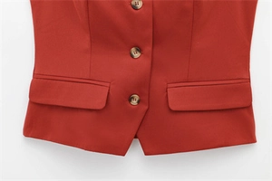 Detail view of brick red suit vest featuring three tortoise buttons and flap pockets