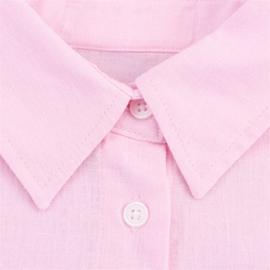 Macro d'un col de chemise rose clair avec coutures précises et boutons en résine