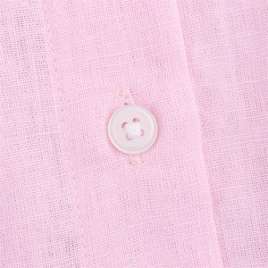 Vue macro de la texture du lin rose et détail d'un bouton à quatre trous assorti
