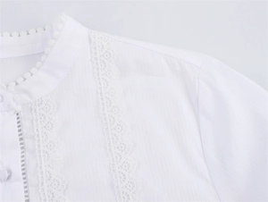 Detail der weißen Spitze Bluse mit Stehkragen, Bommelbesatz und hohlen Spitzenmustern