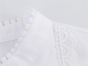 Detail eines weißen Hemdkragens mit Pompon-Borte und feiner Spitzennaht an der Schulter