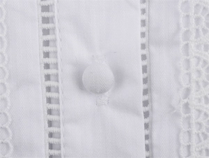 Detail der weißen Baumwollbluse mit Spitzenbesatz, Stoffknöpfen und Stickerei
