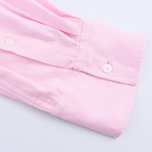 Gros plan détaillé d'un poignet de chemise rose clair avec coutures et boutons blancs