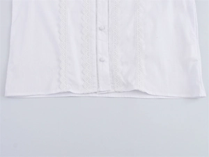 Detailansicht der weißen Baumwollbluse mit eleganten Spitzendetails und Stoffknöpfen