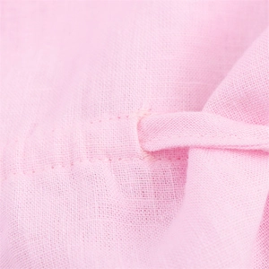 Détail macro du tissu en lin rose montrant l'oeillet et le cordon de serrage assorti