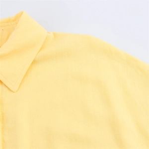 Gros plan détaillé du col et de l'épaule d'une chemise jaune pâle en tissu naturel
