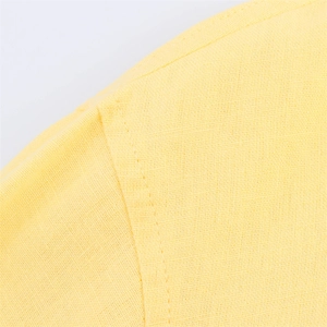 Détail macro de la texture du tissu jaune vif et des coutures précises sur la chemise