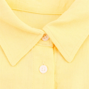 Détail macro du col d'une chemise en lin jaune avec coutures nettes et boutons blancs