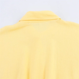 Détail du col à revers jaune pâle et des coutures soignées sur la chemise en coton