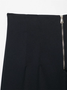 Dettaglio dei pantaloni neri a vita alta con cerniera laterale dorata su tessuto elegante