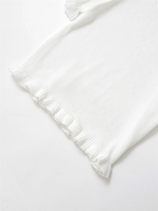 Gros plan sur un pull en maille blanche avec ourlet à volants et détails de texture