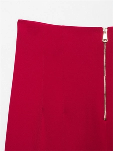 Dettaglio di pantaloni rossi a vita alta con cerniera triangolare in metallo dorato