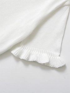 Détail de la manchette d'un pull en tricot blanc avec bords volantés et texture douce