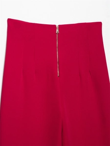 Dettaglio dei pantaloni rossi a vita alta con zip in metallo e pinces sartoriali