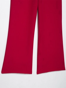 Dettaglio dell'orlo di pantaloni dritti rosso scuro in tessuto liscio con caduta fluida