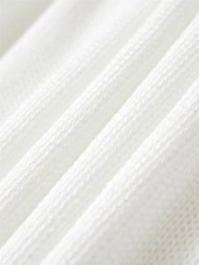Détail macro du tissu en maille côtelée blanche montrant la texture douce et le tissage