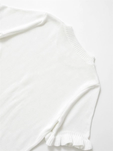 Détail d'un pull en maille blanche avec des poignets à volants élégants et texture douce