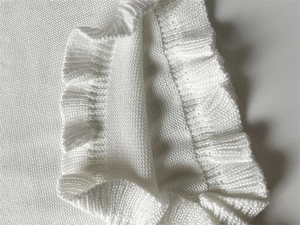 Gros plan d'un pull en maille blanc avec des détails de volants délicats aux poignets