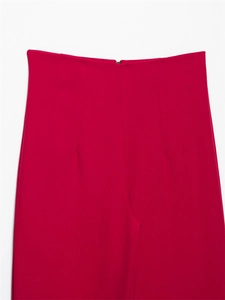 Dettaglio dei pantaloni a vita alta magenta con trama liscia e chiusura lampo centrale