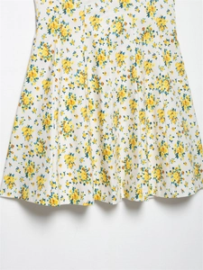 Detalle del dobladillo del vestido de popelina con flores amarillas sobre blanco