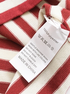 Gros plan de l'étiquette de soin et de la texture 100% polyester du T-shirt rayé