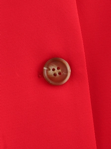 Dettaglio del tessuto rosso del gilet con bottone marrone tartarugato di qualità
