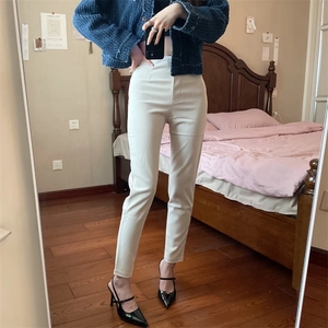 Dettaglio dei pantaloni bianchi a vita alta slim con eleganti bottoni dorati