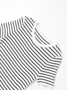 Dettaglio macro di polsini a coste e girocollo su top in maglia a righe bianche e nere