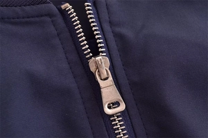 Makrodetail des silbernen Metallreißverschlusses an einer dunkelblauen Baseballjacke