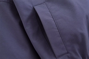 Detailaufnahme einer marineblauen Bomberjacke mit verstärkten, doppelt genähten Taschen