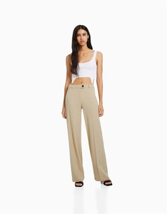 Détail d'un pantalon large kaki à taille haute avec pli frontal et bouton noir élégant
