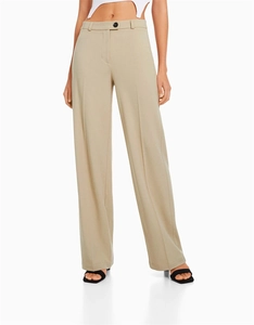 Détail du pantalon large à taille haute avec pli central marqué et bouton noir contrastant