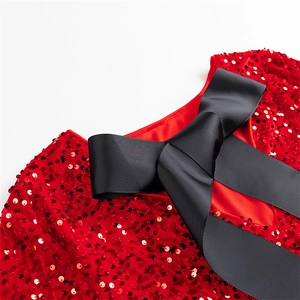 Détail de robe à paillettes rouges avec un grand nœud en ruban noir sur l'encolure