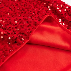 Détail d'une robe rouge à paillettes montrant la texture et la couture de bordure