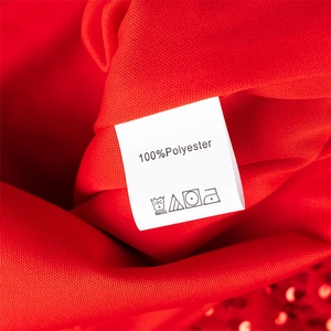 Détail d'une robe rouge à paillettes avec étiquette d'entretien et texture du tissu