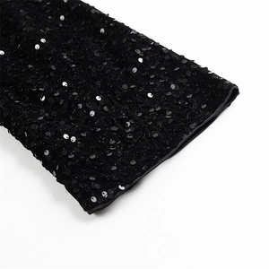Détail de la manche d'une robe noire à paillettes montrant la texture et les finitions