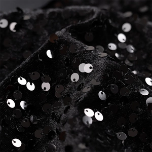 Détail macro de paillettes noires scintillantes sur le tissu en velours de la robe