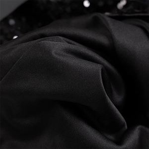 Vue macro de la texture de soie noire avec d'élégantes décorations pailletées sur la robe