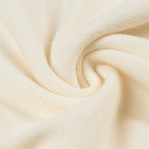 Gros plan sur un tricot beige doux montrant la texture fine et la douceur du tissu