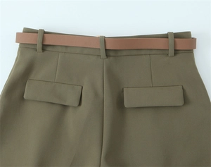 Dettaglio delle tasche posteriori dei pantaloni olive con sottile cintura marrone