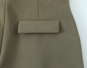 Dettaglio ravvicinato di pantaloni verde oliva con tasca a patta e trama in twill