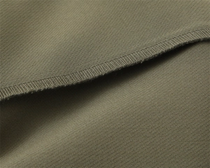 Dettaglio ravvicinato della trama in twill verde oliva e cuciture overlock professionali