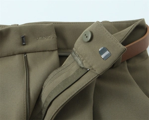 Dettaglio vita dei pantaloni verde oliva con gancio in metallo e cintura in pelle marrone