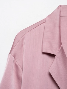 Detailopname van roze blazer met kreukeleffect, verticale plooien en reversdetail