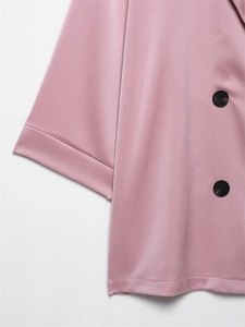 Detail van roze blazer met getextureerde stof en dubbelrijige zwarte harsknopen op de mouw