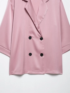 Detail van de roze satijnen blazer met korte mouwen, reverskraag en zwarte dubbele knopen