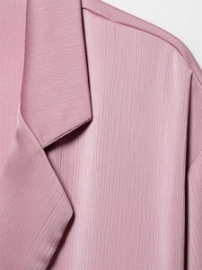 Detail van zachtroze chiffon textuur met rimpel-effect en afwerking van de revers